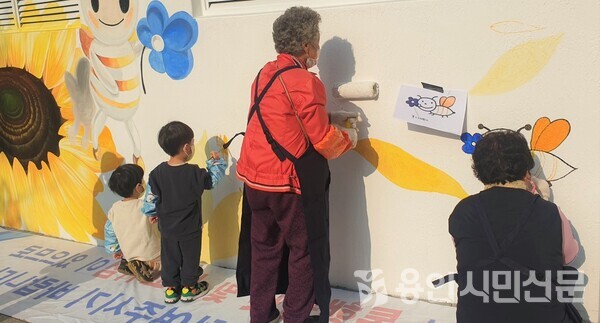 어린이들과 노인이 치매안심마을인 죽전1동 도담마을에 벽화를 그리고 있다.